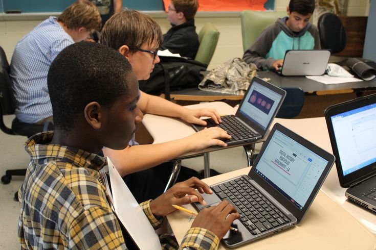 High school students analyzing real-time climate policy data on interactive laptops during a simulated summit